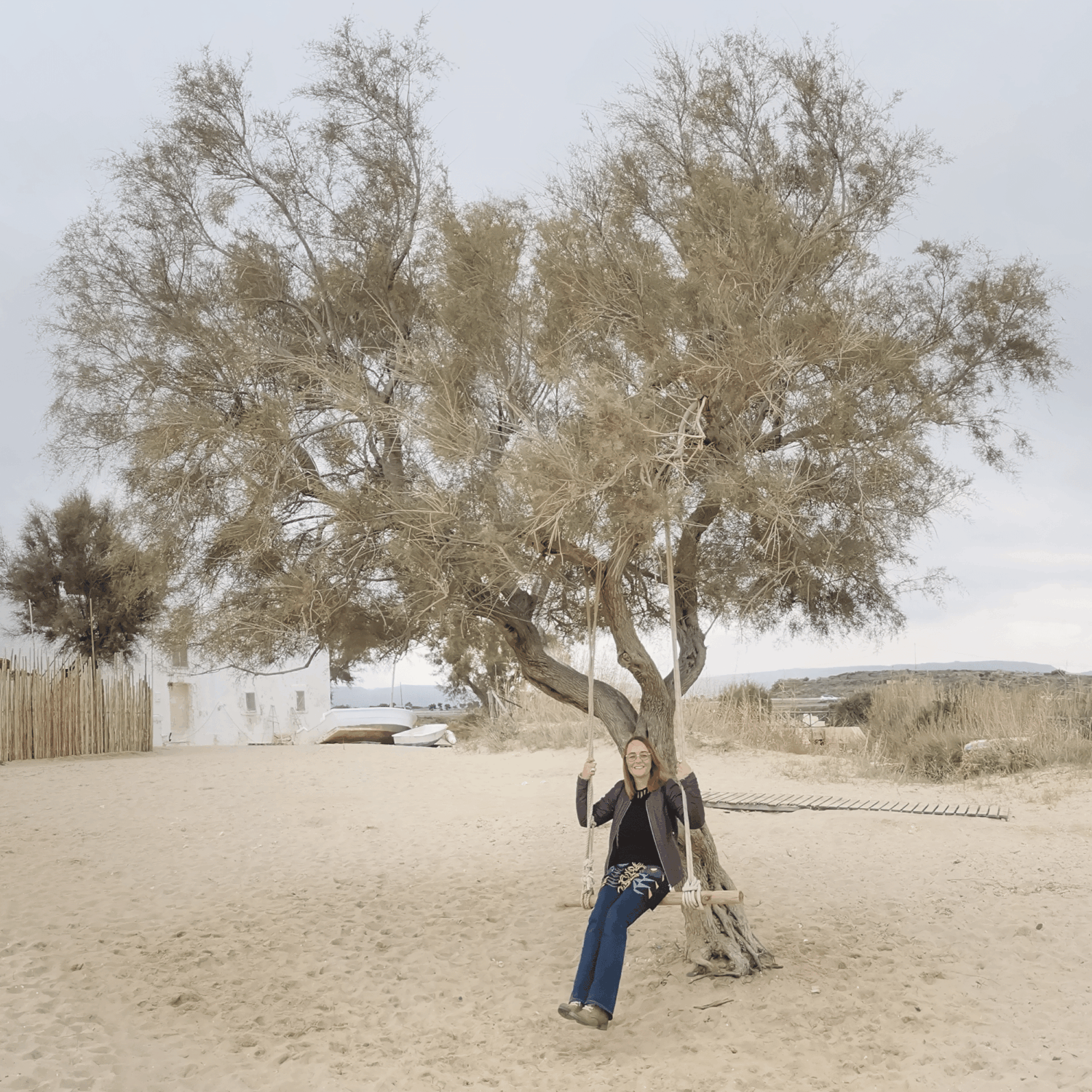 Vrouw (Mandy) zittend op een boomschommel die vriendelijk glimlachend naar de camera kijkt